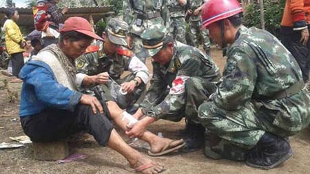 Cảnh sát Trung Quốc hỗ trợ một phụ nữ bị thương vì động đất ở Vân Nam.